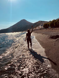 Rear view of man and woman at beach against sky
