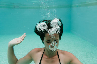 Portrait of shirtless man holding bubbles in swimming pool