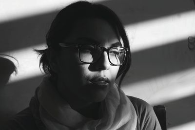 Close-up of thoughtful young woman wearing eyeglasses at home