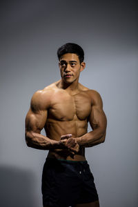 Portrait of young man standing against gray background