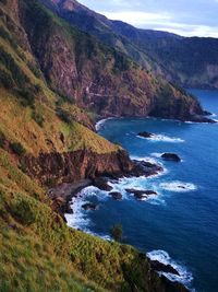 Scenic view of sea by mountains against sky