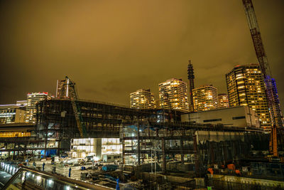 Illuminated modern buildings against sky at night