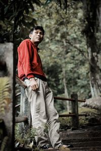 Full length of young man looking away against trees