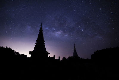 Silhouette temple against building at night