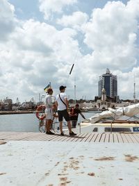 People standing on sea by city against sky