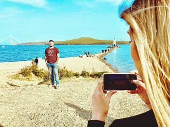 Man photographing at beach against sky