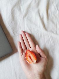 High angle view of hand holding a strawberry cut in half