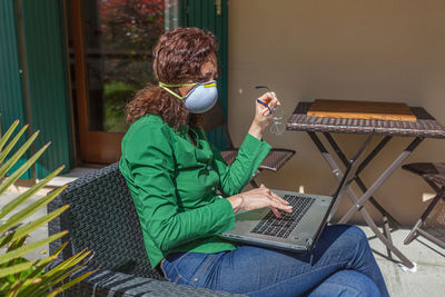 Woman using laptop sitting on chair at home