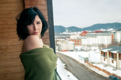 Portrait of topless woman with blanket standing in balcony