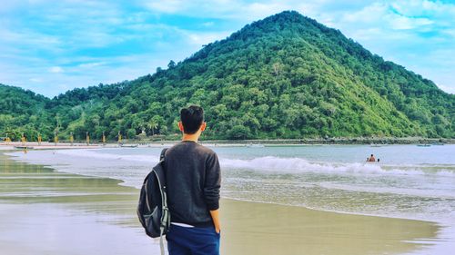 Rear view of man looking at sea against sky