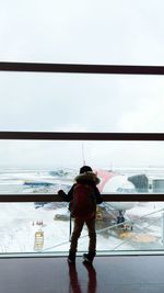 Rear view of man standing on airport against sky