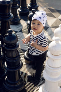 Child in a striped shirt plays with large chess pieces