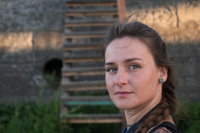 A thoughtfully smiling young woman of slavic appearance with green blue eyes and braided brown hair