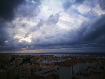 Aerial view of cityscape against cloudy sky