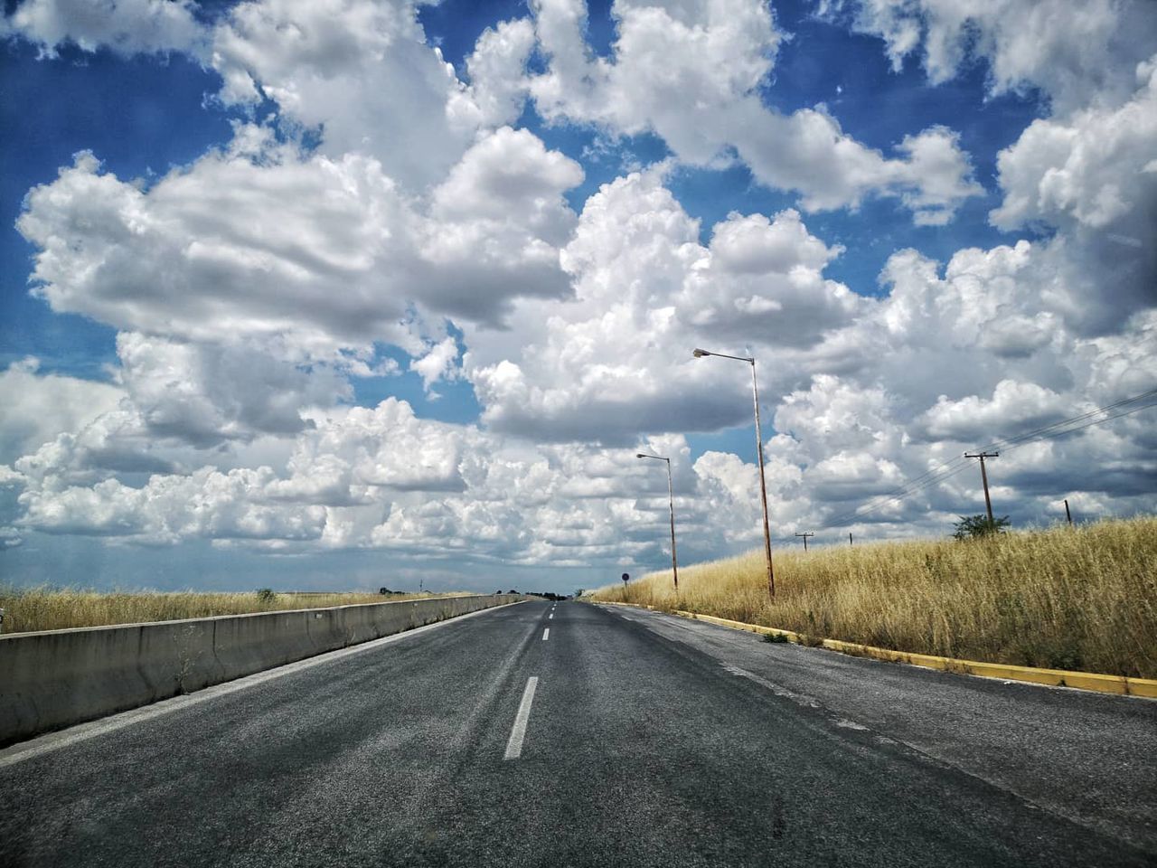 cloud, transportation, road, sky, horizon, the way forward, highway, diminishing perspective, nature, vanishing point, symbol, road marking, landscape, marking, environment, travel, infrastructure, no people, sign, day, freeway, road trip, asphalt, mode of transportation, street, scenics - nature, country road, land, empty road, non-urban scene, beauty in nature, blue, outdoors, cloudscape, dividing line, journey, rural scene, car, motor vehicle, plant, tranquility, travel destinations, tranquil scene, sunlight, horizon over land, lane