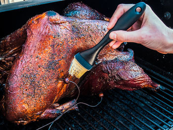 Close-up of person preparing food on barbecue grill