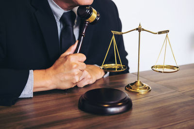 Midsection of lawyer holding gavel at desk in courthouse