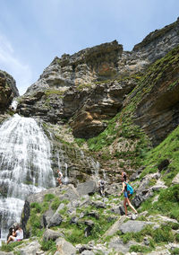 Rear view of people walking on rocks by mountain