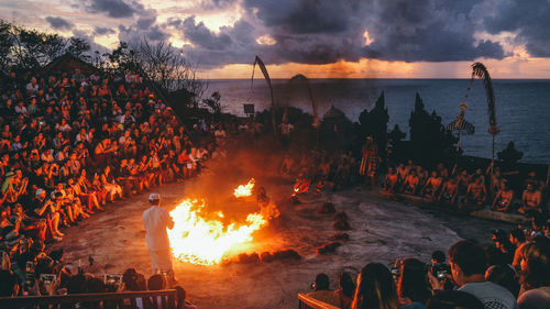 Panoramic view of people by sea against sky during sunset