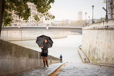 Brunette girl in a black jacket walks on the river embankment