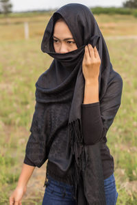 Portrait of young woman standing on field