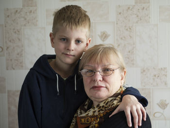 Portrait of grandmother and grandson against wall at home