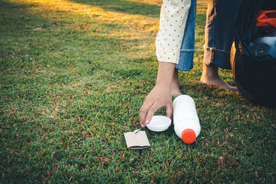 Low section of woman holding umbrella on field