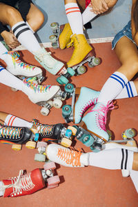 Legs of women wearing colorful roller skates at sports court