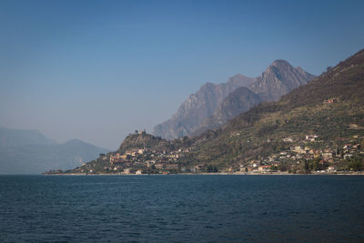 Scenic view of sea by mountains against clear sky