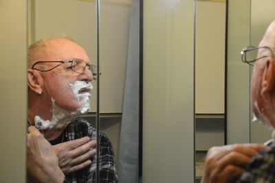 Man looking at mirror while shaving in bathroom