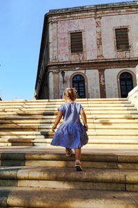 Rear view of woman walking on staircase against building