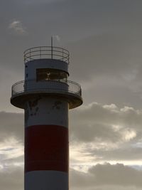 Lighthouse by sea against sky during sunrize