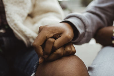 Cropped image of female friends holding hands outdoors