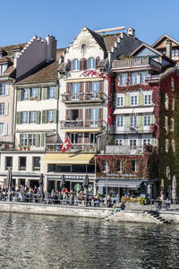 Buildings by river against sky in city