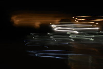 Blurred motion of illuminated lights on table against black background