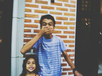 Portrait of smiling woman standing against wall