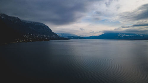 Scenic view of sea by mountain against sky