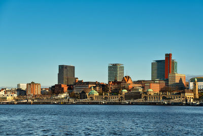 River by modern buildings against clear blue sky