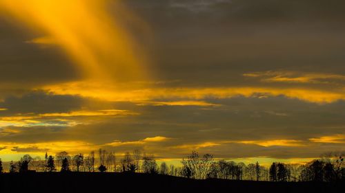 Silhouette landscape against dramatic sky during sunset