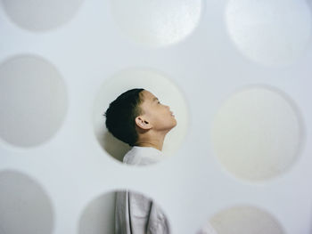 Portrait of a boy behind a perforated white partition