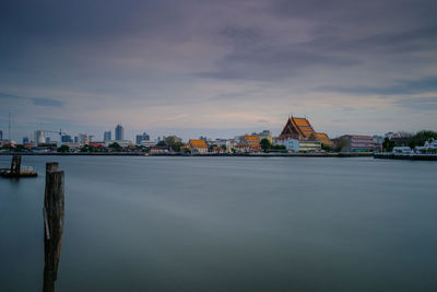 River by buildings against sky during sunset