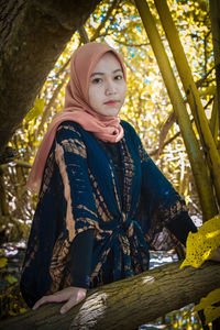 Portrait of beautiful young woman against tree