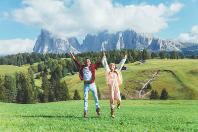 Man with arms raised on mountain against sky