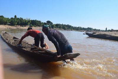 People working on boat against clear sky