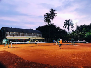 People playing soccer on field against sky