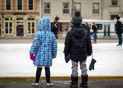 Rear view of two people walking in front of building