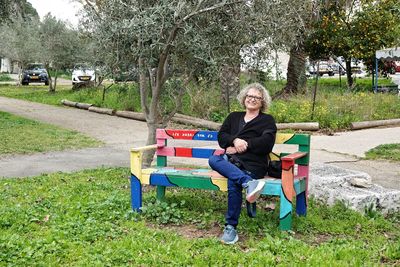 Portrait of woman sitting on bench in park