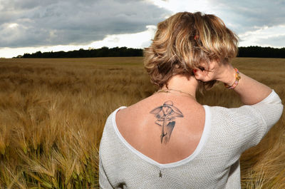 Rear view of woman standing on field against sky