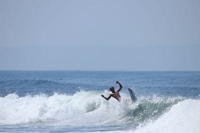 Man surfing in sea against sky