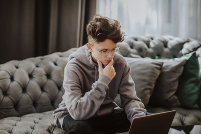 Student with hand on chin e-learning through laptop at home